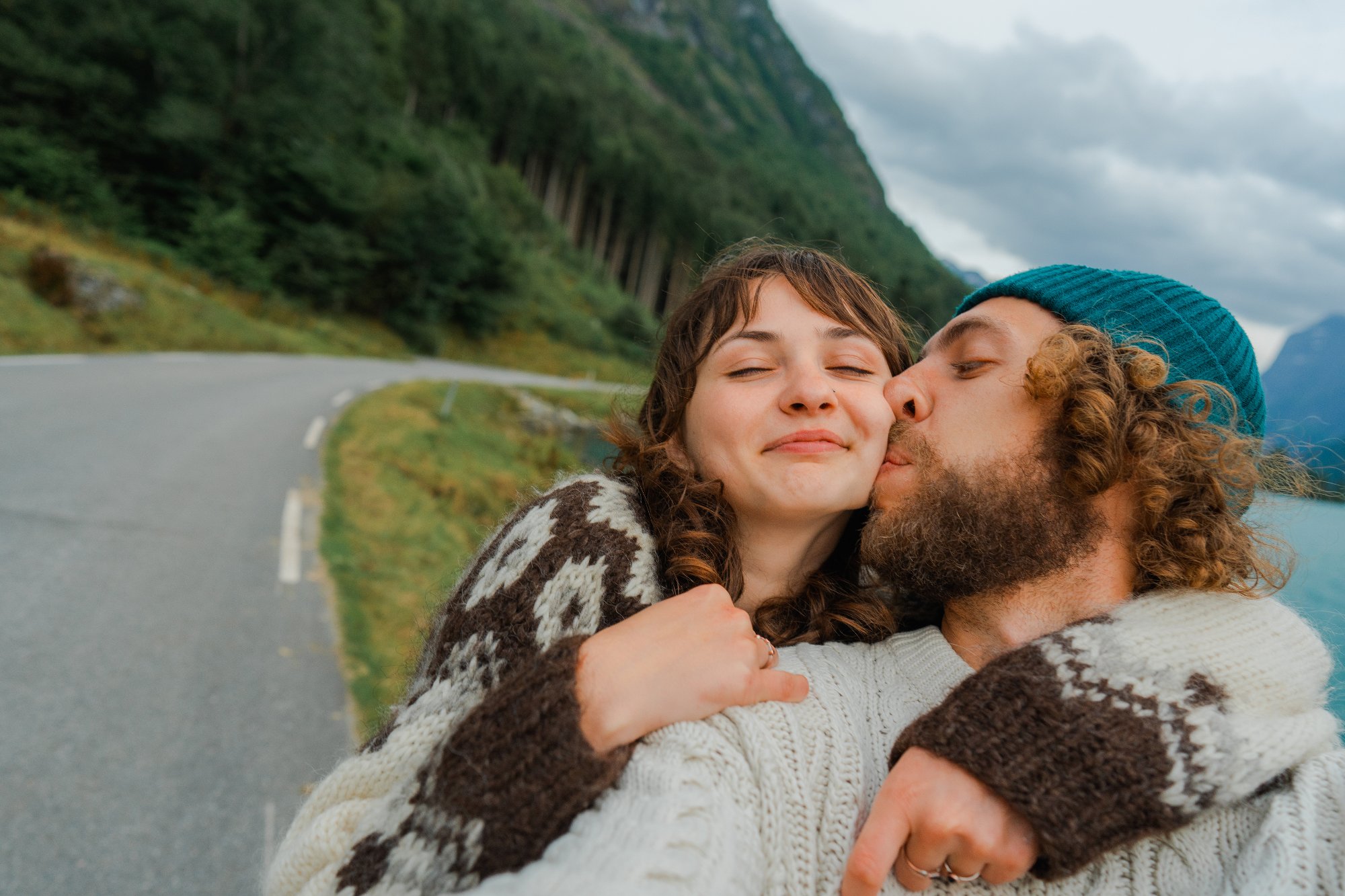 Selfie of man and woman in knitted sweaters  having road trip and   traveling in Norway
